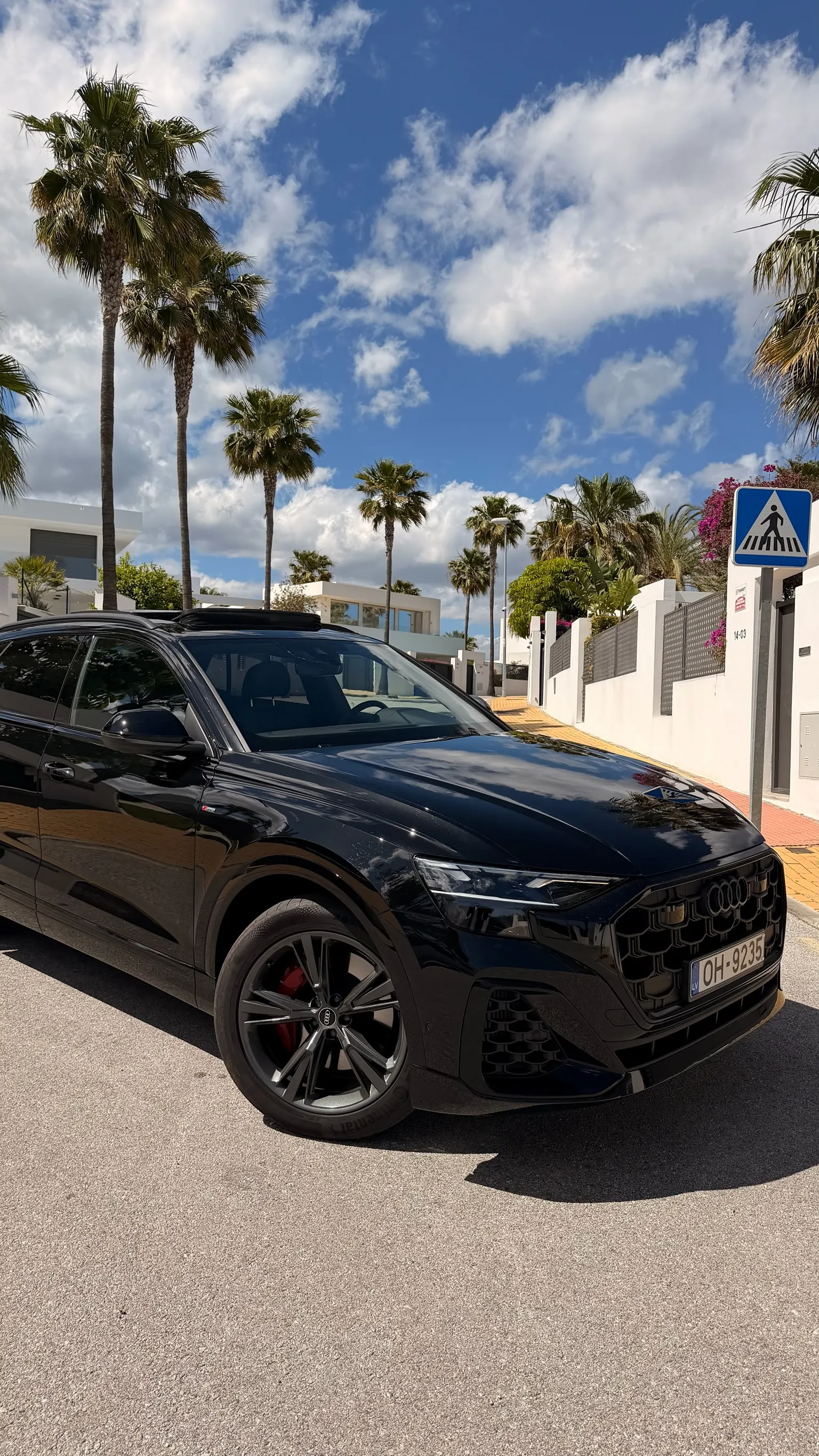 Close-up front three-quarter view of the Orca Black metallic Audi Q8 with octagonal Singleframe honeycomb grille, 22-inch 5-twin-spoke anthracite wheels and red Brembo caliper