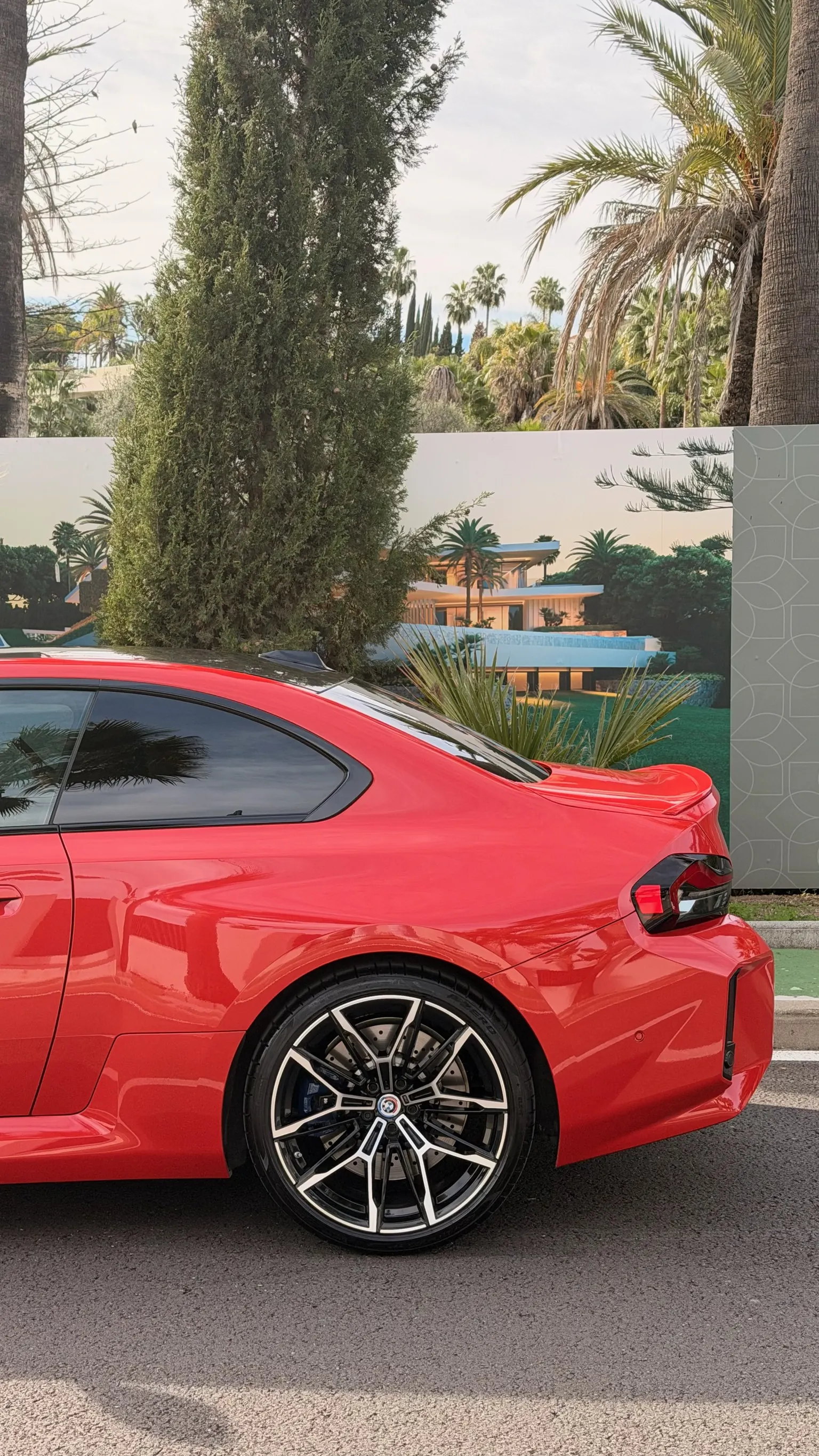 Rear three-quarter view of the red BMW M2 G87 with close-up M wheel and blue brake caliper