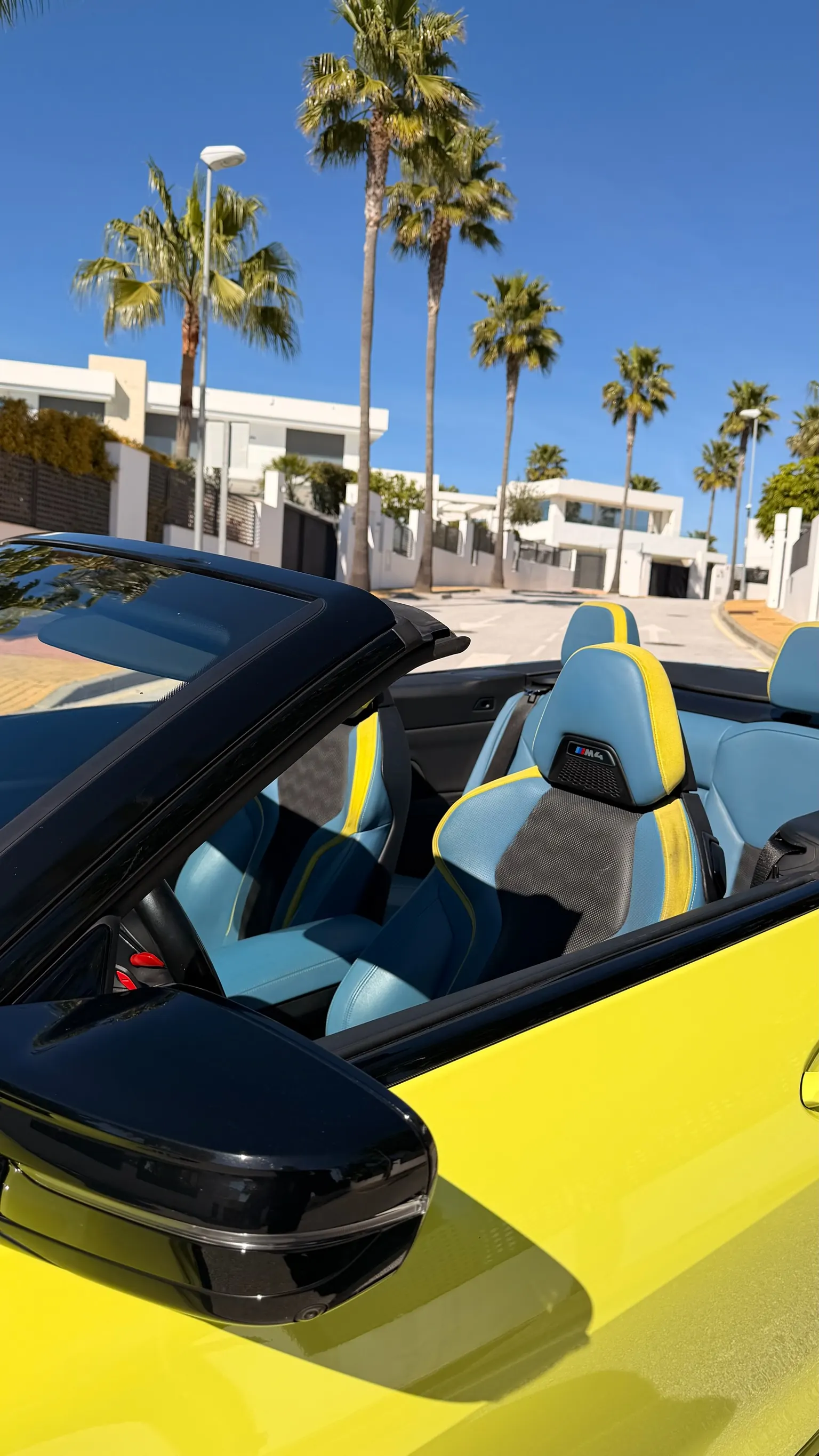 Top-down view of the BMW Individual blue and yellow leather interior of the M4 Convertible with Marbella backdrop
