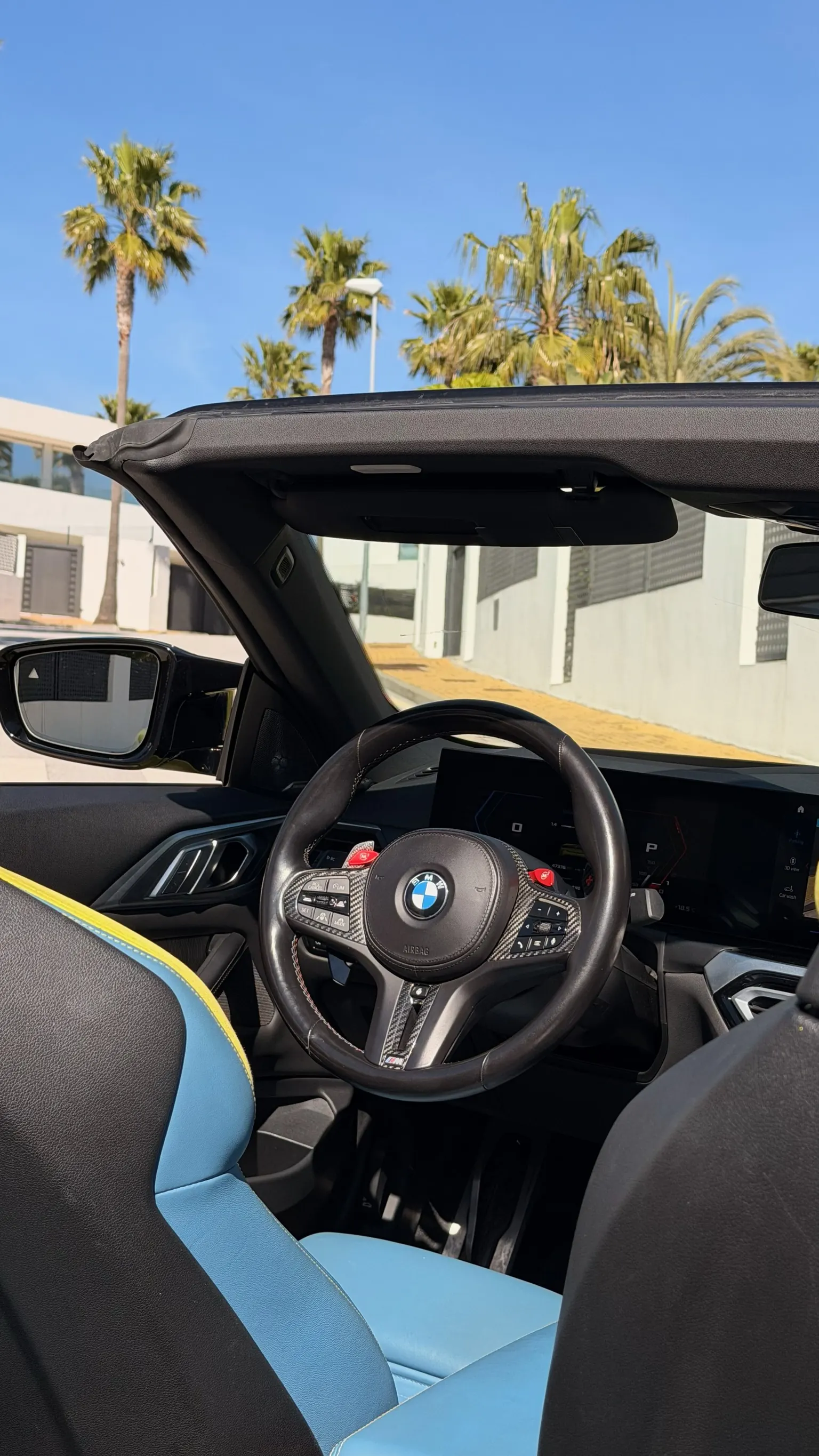 BMW M4 Convertible cockpit with carbon M steering wheel, BMW Curved Display instrumentation and BMW Individual blue leather driver seat