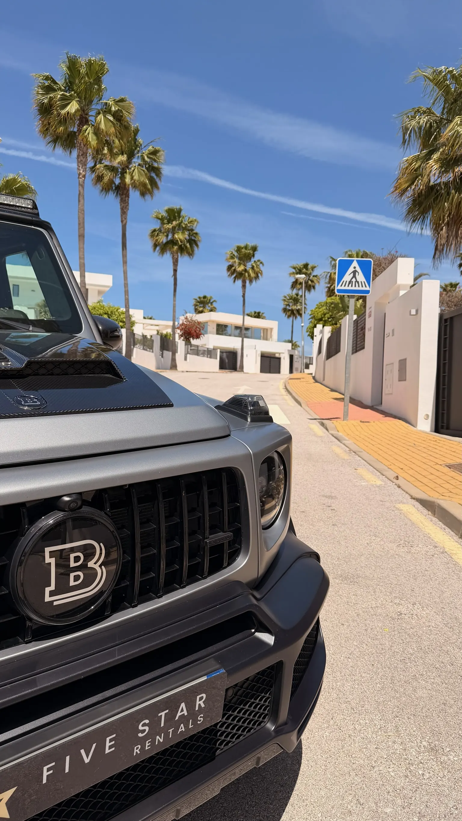 Brabus grille with B logo and Five Star Rentals license plate, carbon hood visible