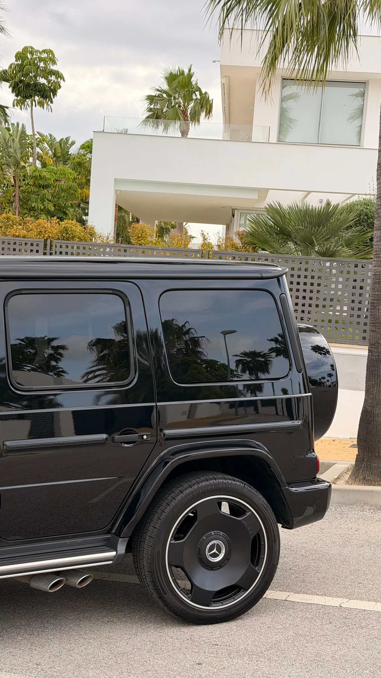 Side profile of the black Mercedes-AMG G63 with AMG stainless side steps, 22-inch black AMG wheel and side-exit dual exhaust