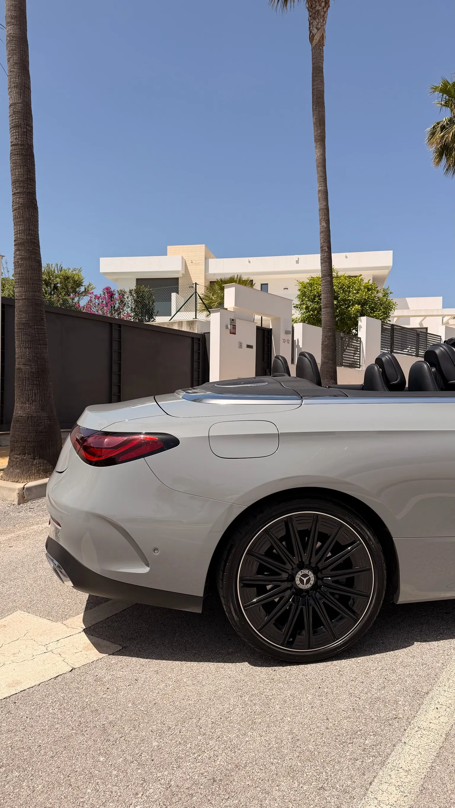 Rear side profile of the Alpine Grey CLE 200 Cabriolet with top down, 19-inch black multi-spoke AMG wheel and LED light bar