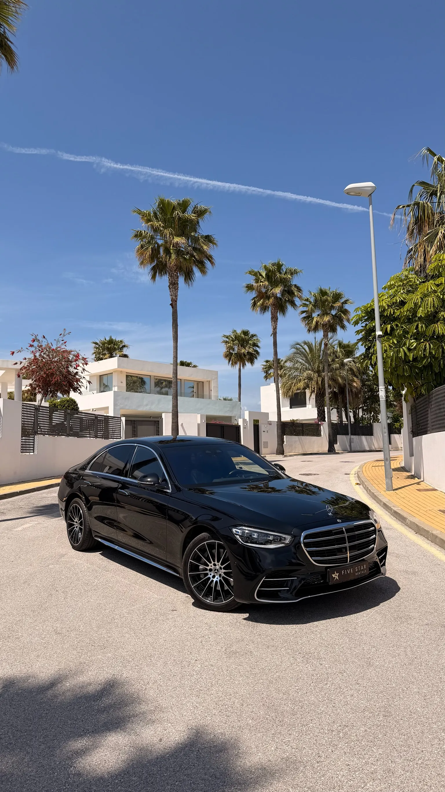 Mercedes-Benz S-Class S 580 e in Obsidian Black, front three-quarter view with chrome grille, Five Star Rentals plate and Marbella palm trees