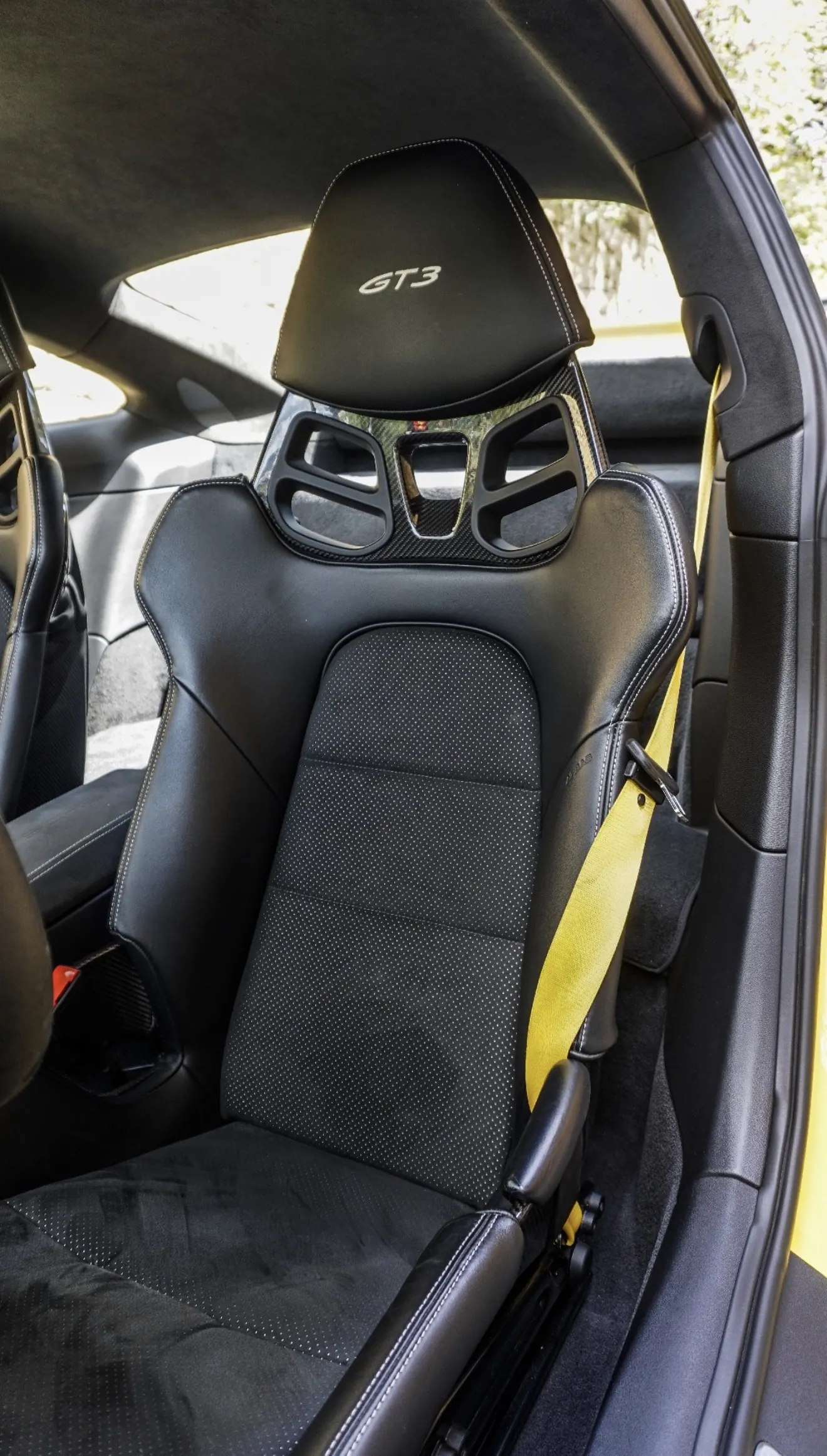 Porsche 911 GT3 992 sport bucket seat in perforated black leather with embroidered GT3 headrest logo, carbon backrest and Racing yellow seat belt matching the bodywork