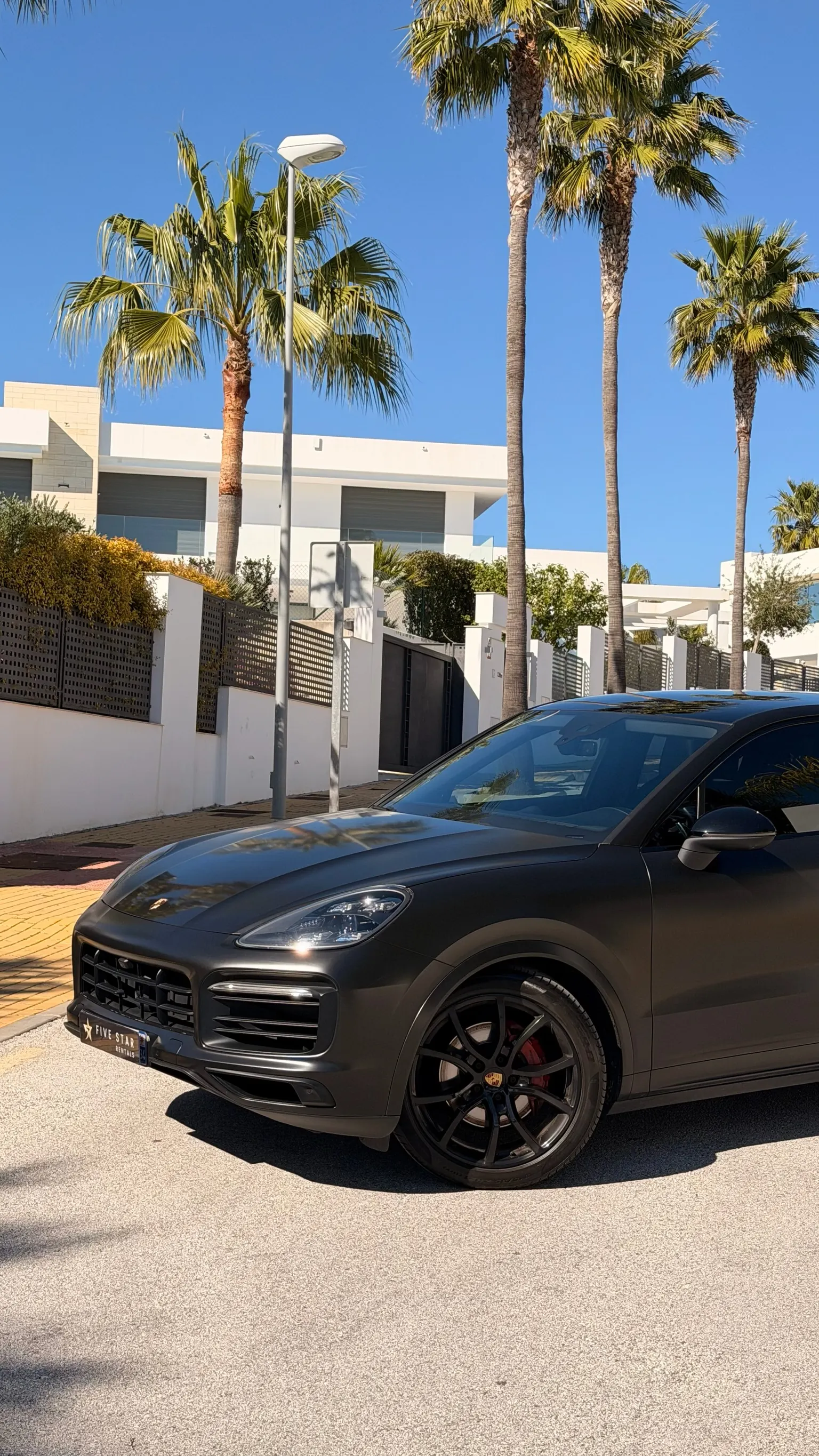Front detail of the matte black Cayenne Coupé with LED headlights, 21-inch black wheel and red brake caliper