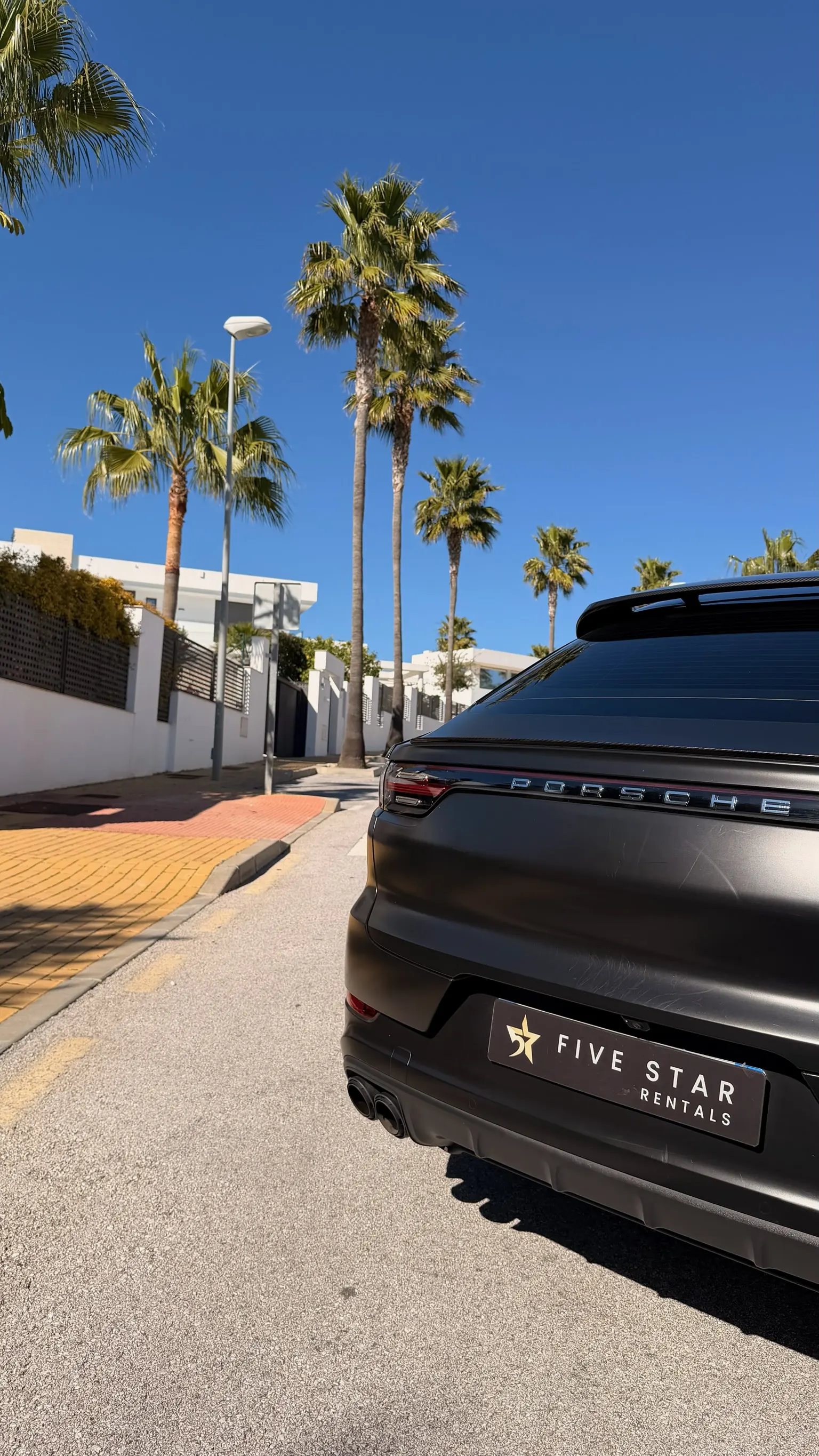 Rear detail of the matte black Cayenne Coupé with illuminated PORSCHE light bar, sport diffuser and Five Star Rentals plate
