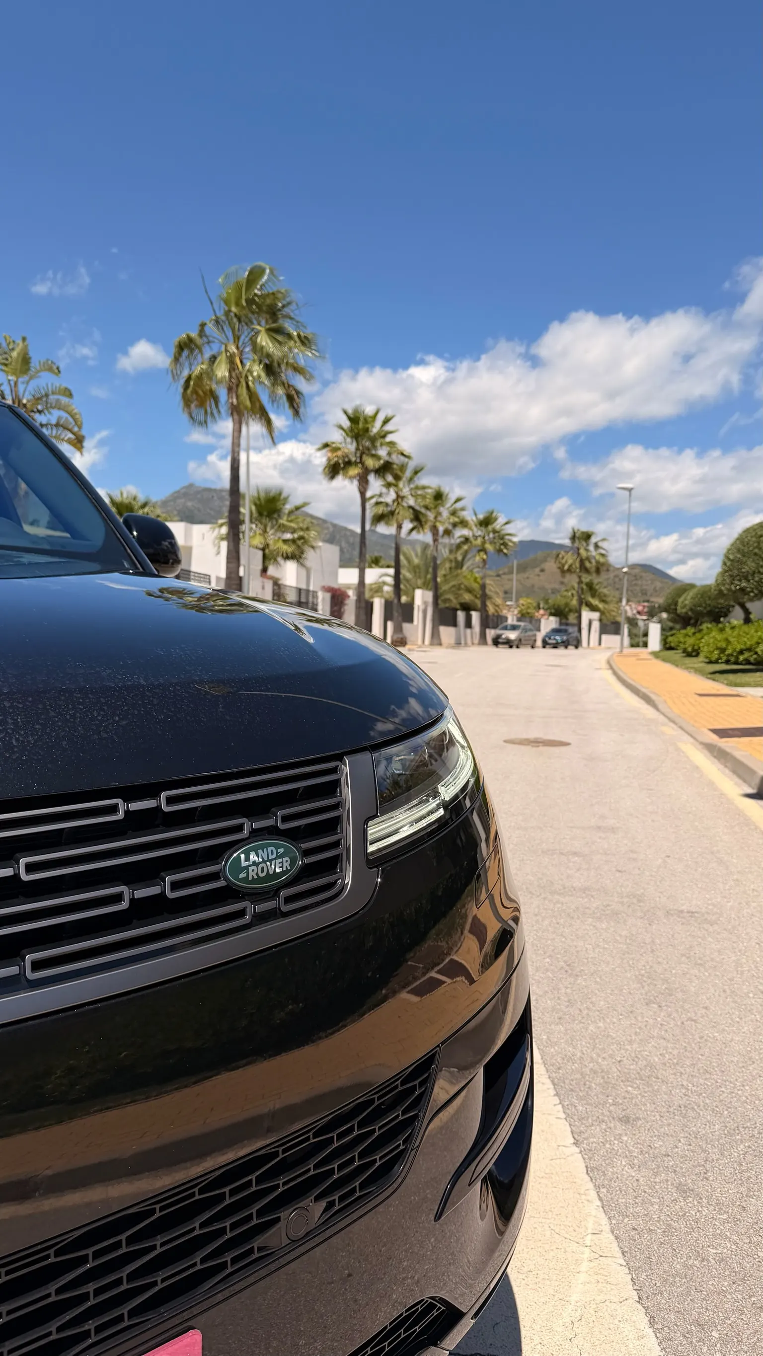 Range Rover Sport front detail in black with green oval Land Rover logo and horizontal black slat grille