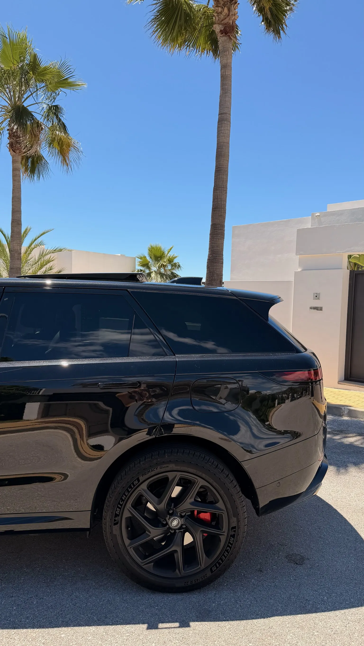 Rear side profile of the Santorini Black Range Rover Sport P460e with sloping roofline, 22-inch wheel and integrated rear LED light bar