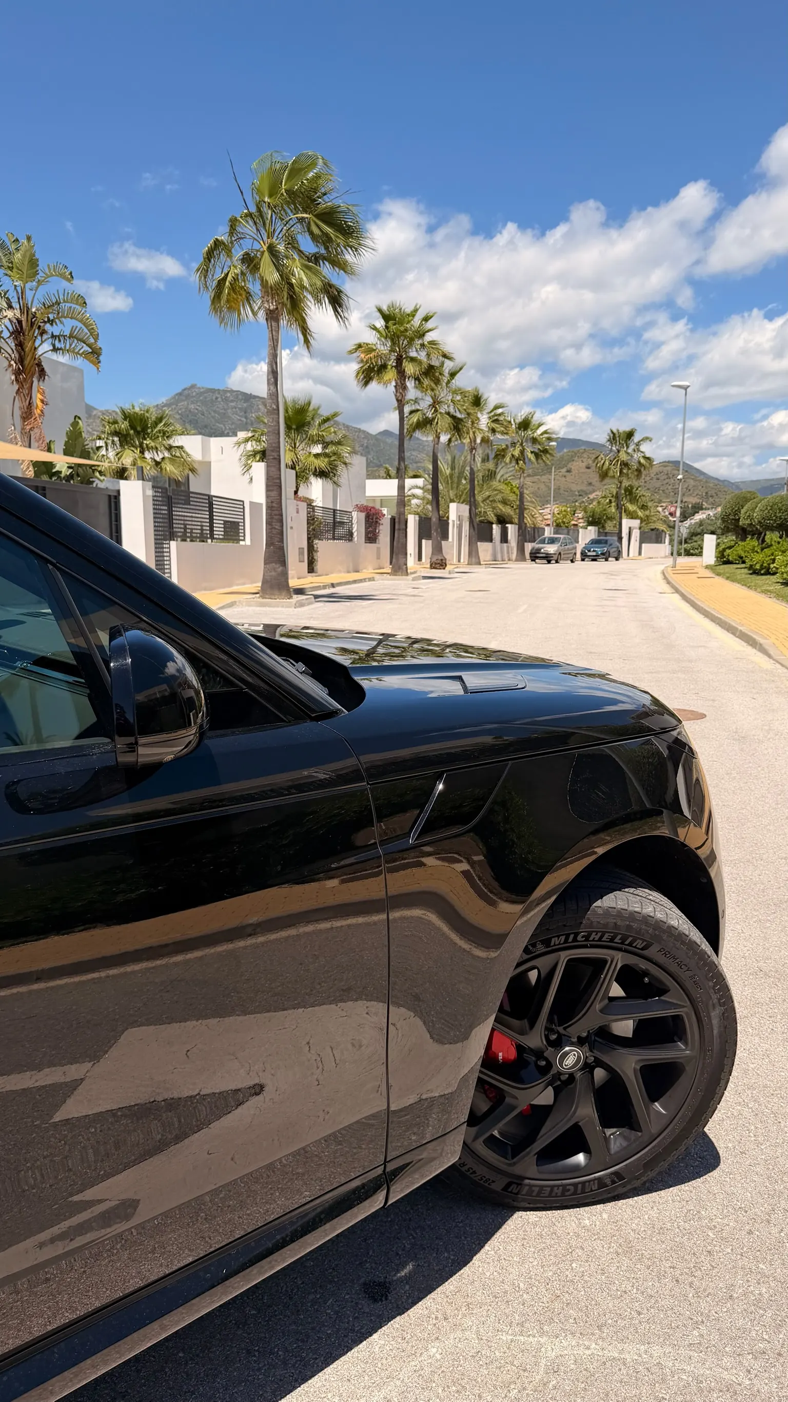 Range Rover Sport front left fender detail with signature black side vent, 22-inch 5-spoke star wheel and red brake caliper
